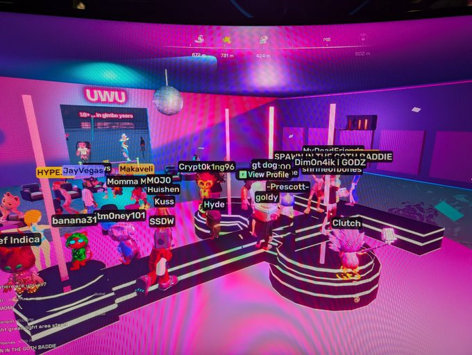 A vibrant pink and purple virtual environment, likely Decentraland, showing avatars with usernames like 'HYPE JayVegas75', 'Momma MMOJO', and 'Dim0n4ik' gathered in a virtual space.