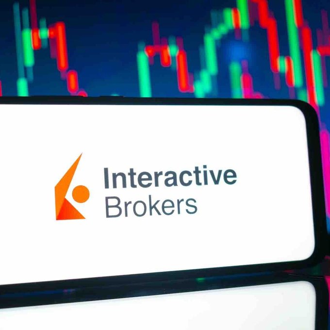 The image displays the Interactive Brokers logo on a smartphone screen, set against a backdrop of colorful trading charts, visually reinforcing the post's announcement about the brokerage expanding its services to include Ethereum staking for its millions of clients.