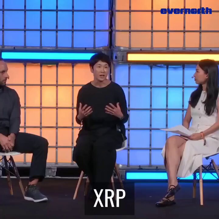 The image shows three people sitting around each other at a table with chairs. They are engaged in conversation, possibly discussing the XRP cryptocurrency or its features. The background of the image has blue and orange panels that create an interesting visual effect. The text "MEG NAKAMURA JUST SAID WHAT NEEDED TO BE SAID!" suggests that someone was talking about XRP during their discussion.