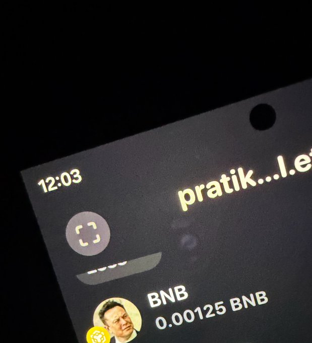 A close-up of a smartphone screen displaying the time 12:03, a Face ID icon, a BNB wallet balance of 0.00125 BNB, and partial text reading 'pratik...I.e'.