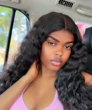 A young woman with long, voluminous wavy hair sits in the back of a car, wearing a pink top, reflecting a polished and confident "after" look compared to the implied humbler "before" mentioned in the caption.
