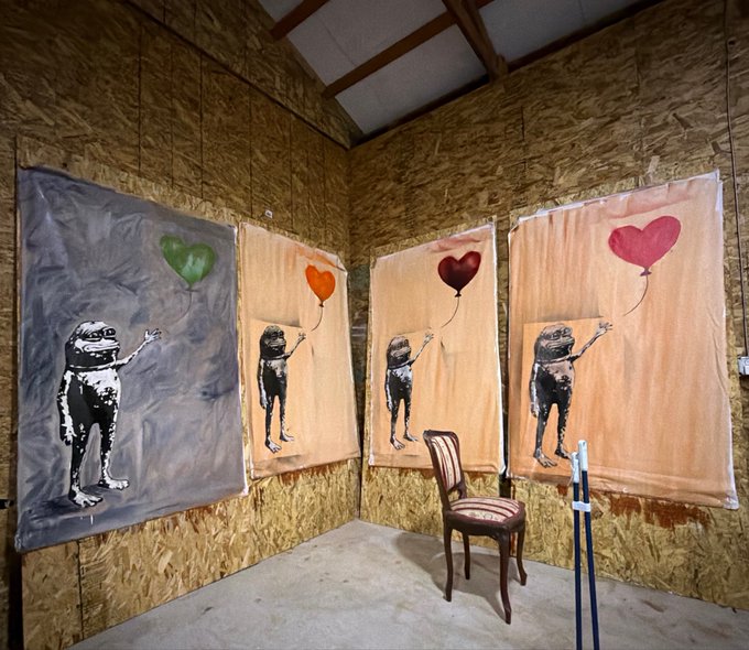 Four canvas paintings of a figure reaching for a heart-shaped balloon are displayed on OSB/particle board walls in what appears to be an unfinished room, with a single wooden chair placed in the center.