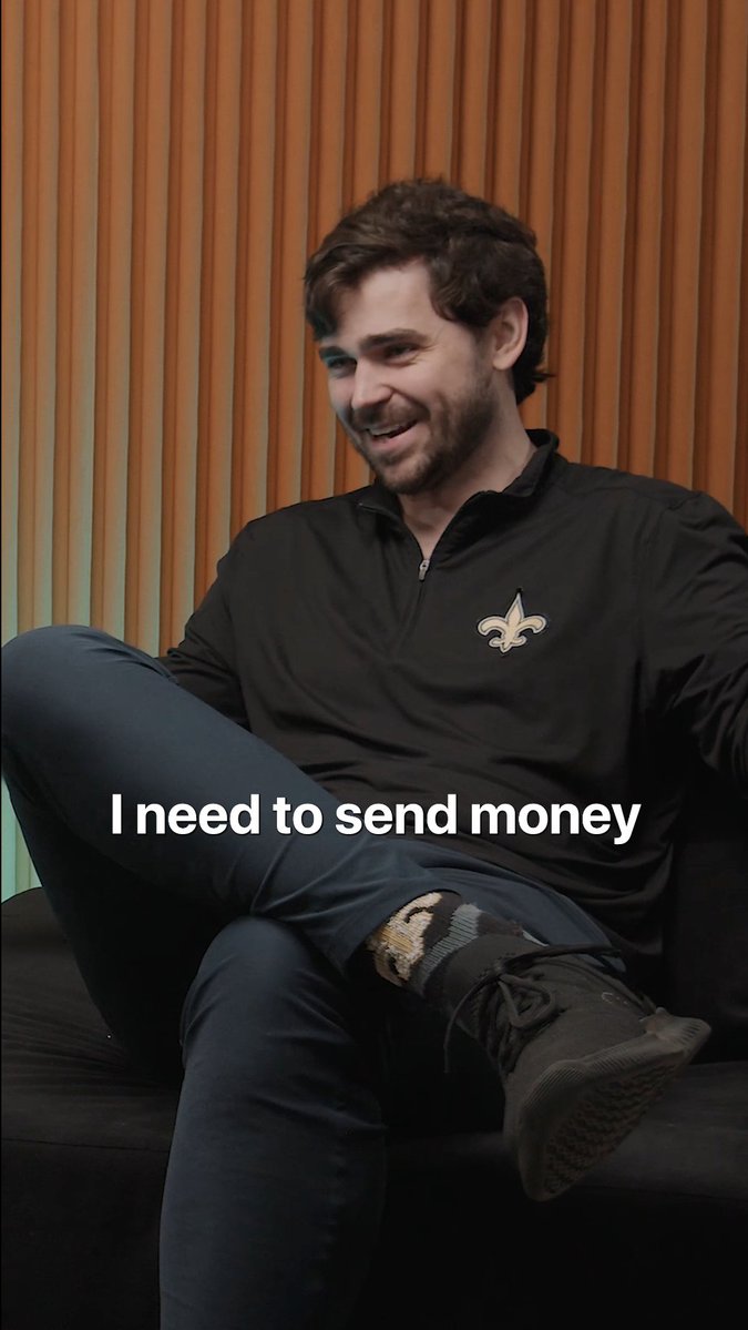 A smiling man in a black quarter-zip top with a fleur-de-lis logo sits casually with the caption "I need to send money" overlaid, visually illustrating the post's theme of cross-border money transfers and financial access in underserved markets.