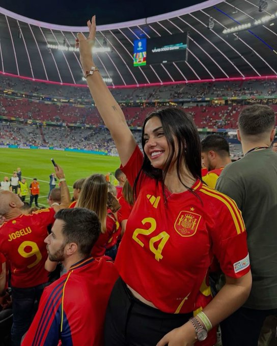 A woman wearing a Spain national team jersey with the number 24 smiles and raises her arm in celebration at a soccer stadium, with a "Joselu 9" jersey visible nearby. The caption suggests she added a Spanish flag to her display name, and the image reflects her pride as a Spain fan, likely after a notable match moment.

Text visible: "24" (jersey number), "JOSELU 9" (jersey name/number), "RESPECT" badge, and stadium signage including "UEFA EURO 2024."