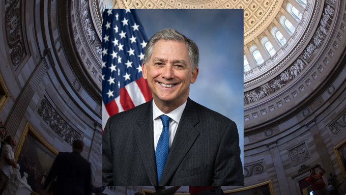 The image features a man dressed in a suit, standing in front of an American flag with the words "United States Capitol" written above him. The man appears to be smiling for the camera, giving off a positive vibe. The caption below the photo reads "#clarityact #XRP".