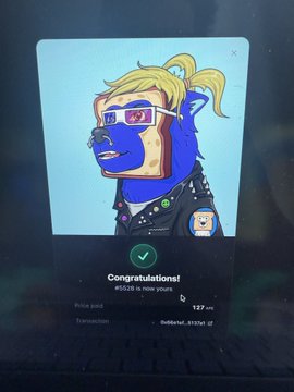 The image shows a digital NFT card from the "Vault" game on a mobile screen, featuring a stylized blue monkey character with blonde hair and sunglasses, with a "Congratulations!" message indicating the user holds #6528 in main journey with 127/127 traits completed. The card relates to the post showing a successful Boggy character acquisition on ApeChain, celebrating the user's addition to their NFT collection.