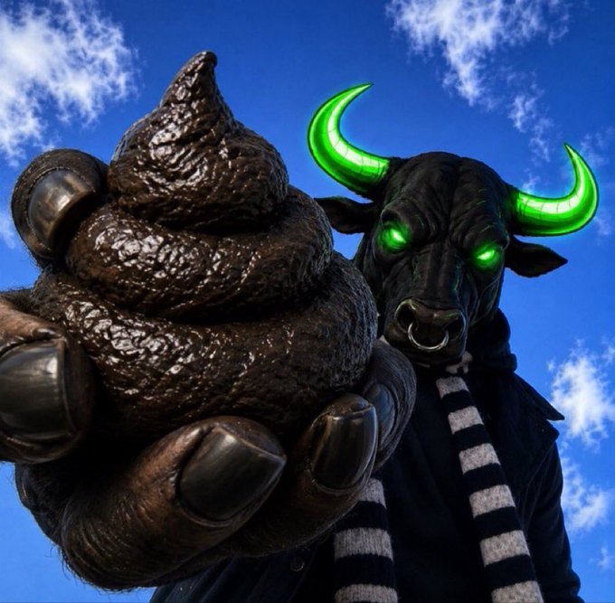 A costumed mascot character with glowing green horns and eyes holds up a large sculpted pile of poop against a blue sky with clouds.