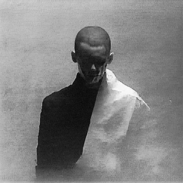 The image shows a man wearing a black and white striped shirt against a gray background. The photo appears to be in black and white, which adds an artistic touch to the scene. The caption provided seems unrelated to the image itself and focuses on other matters.