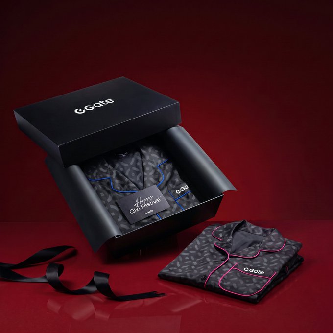 A luxury gift box from GGate is displayed against a red background, containing a patterned pajama set with pink trim and a "Happy Qixi Festival" card, alongside a folded matching garment and a flowing black ribbon—promoting a giveaway tied to the Qixi Festival celebration.
