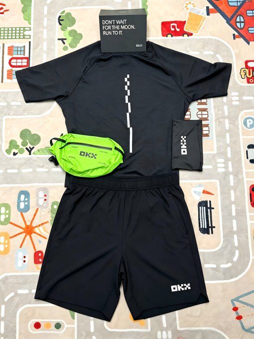 A flat-lay of an OKX running kit, including a black short-sleeve shirt with a dashed line graphic, black shorts, a green waist pack, and a tag reading 'DON'T WAIT FOR THE MOON. RUN TO IT.'