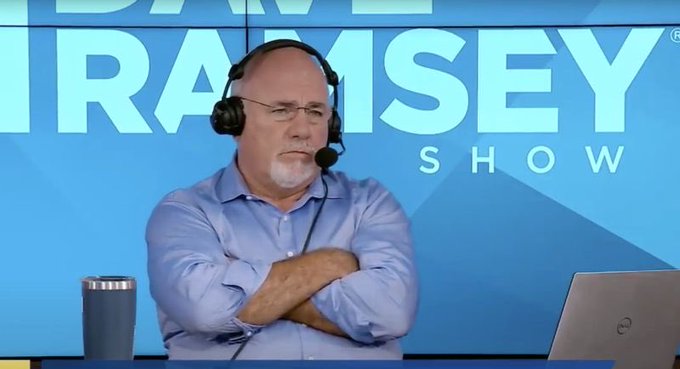 Dave Ramsey, wearing a headset and seated in front of a "Ramsey Show" backdrop, listens with arms crossed and a stern expression as a caller explains losing $10,000 in altcoin cryptocurrency investments.
