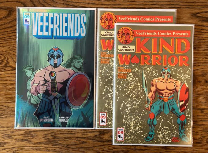 Three comic book covers titled 'VEEFRIENDS' and 'VeeFriends Comics Presents KIND WARRIOR' issue 09, by Gary Vaynerchuk and Katelyn Windels, displayed on a wooden surface.