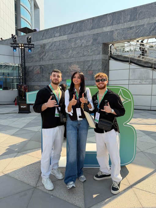 Three people pose in front of a Bing promotional sign at what appears to be a tech event, all giving thumbs up while wearing lanyards. The "GM" caption fits the casual, upbeat vibe of the photo, suggesting a friendly greeting to the community on a sunny day at the venue.