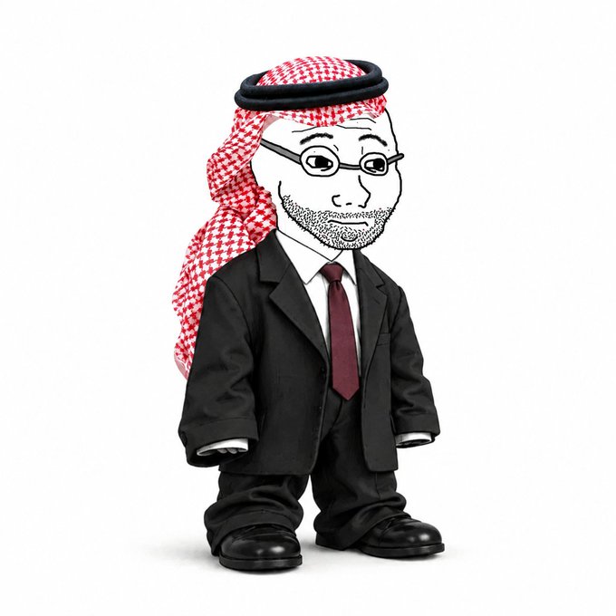 A stylized plush figure wearing a red and white checkered keffiyeh, glasses, a black suit with a red tie, with a cartoon face on a black body.
