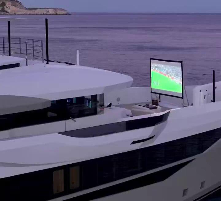 The image shows a large white boat with a flat screen TV mounted on its top deck, overlooking the ocean. The TV displays a sports game, likely soccer or basketball, which appears to be playing on a big screen. The surrounding waters are calm, reflecting the serene atmosphere of the scene. The post in the image is about investing and making money during bear markets, encouraging viewers to accumulate as much cryptocurrency as possible while waiting for the market to recover.