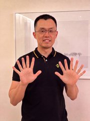 A man in a black polo shirt stands smiling with both hands raised, showing ten fingers spread wide. The celebratory pose visually echoes the post's excitement about $67's milestone achievements and its new deployment on the BNB Chain.