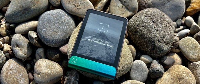 A smartphone displaying "SECURITY IS THE MOST IMPORTANT THING" rests on smooth river rocks, visually echoing the post's critique that self-custody relies on a rigid, gatekept design that demands perfect discipline rather than empowering the permissionless freedom Bitcoin originally promised.