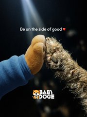 Advertisement showing a dog fist-bumping a human hand with text 'Be on the side of good' and 'BABY DOGE' branding.