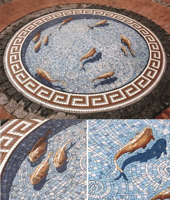 An intricate circular mosaic featuring gold-colored koi fish swimming among blue wave patterns, bordered by a Greek key design, with two close-up detail shots below.