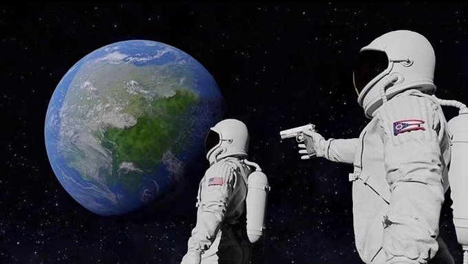 Two astronauts in white spacesuits float in space near Earth, with one pointing a handgun at the other. The astronaut on the left has a US flag patch, while the astronaut on the right has a Puerto Rico flag patch on their sleeve.