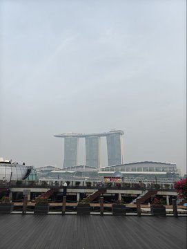 A view of the Marina Bay Sands hotel in Singapore on a hazy day, with a wooden boardwalk in the foreground.