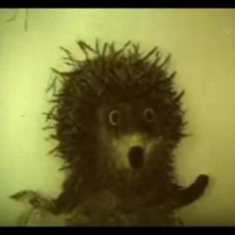 A spiky, cartoonish dark creature with wide eyes stares directly at the camera, evoking a somewhat eerie or unsettling vibe. The image's mysterious, creature-like aesthetic ties into the post's tone of unmasking the "real" identity behind the @FuzzybearBTC handle, suggesting a reveal of the true figure amid accusations of impersonation by XRPL "grifters."