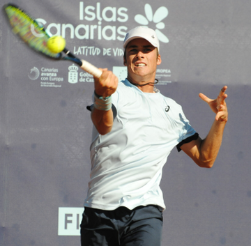 A tennis player swings into a forehand against a backdrop reading "Islas Canarias Latitud de Vida." The action shot visually reflects the Polymarket trader's high-stakes wagers on US Open qualifying matches involving players like Vilius Gaubas and Toby Samuel.