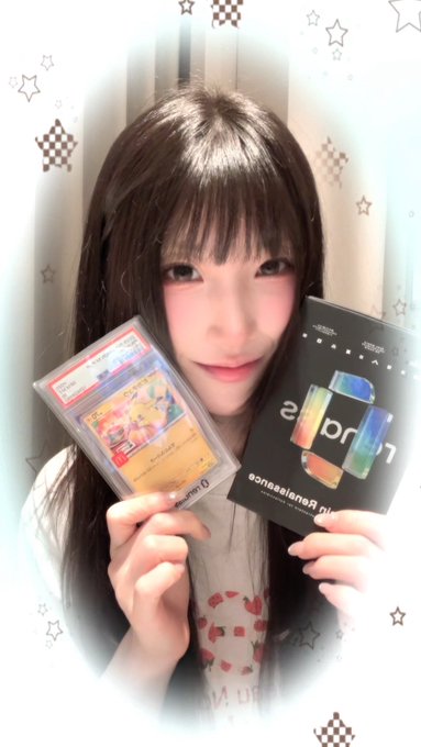 A young woman holds up a graded Pokémon trading card in a PSA slab and a custom promotional card.