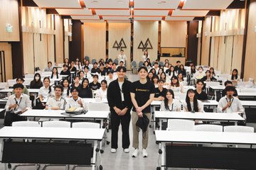 Two representatives from Binance Academy stand at the front of a packed lecture hall at Kasetsart University, Thailand, surrounded by students seated at rows of desks during the University Tour event focused on Bitcoin, risk, regulation, and institutional adoption.