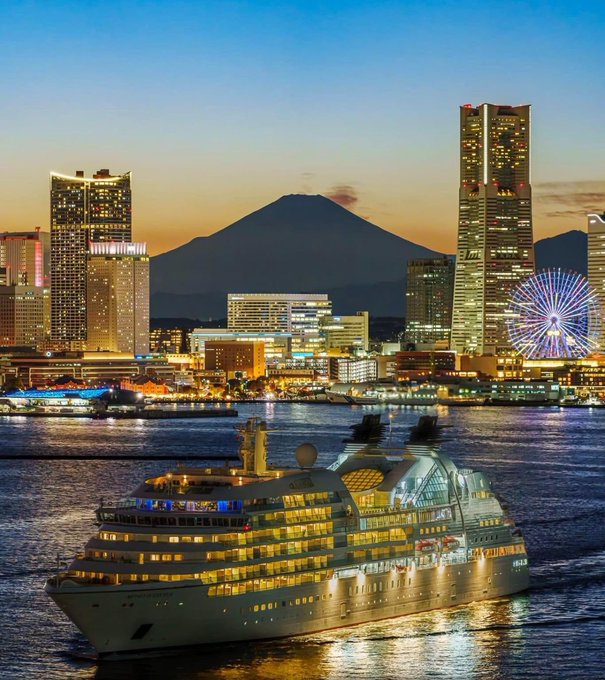 The image shows a large cruise ship sailing through a city at night with tall buildings surrounding it. The ship appears to be passing by a volcano, adding an element of natural beauty to the urban landscape. The caption suggests that there might be some security challenges or concerns related to the cruise ship's presence in the area, and the post is likely discussing these issues before they become emergencies.

The image also features a ferris wheel, which adds to the cityscape's visual appeal. The combination of natural elements like the volcano and man-made structures such as the ferris wheel creates an interesting contrast between nature and urban development.