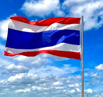 A Thai flag flutters against a blue sky with scattered clouds, symbolizing Thailand as the SEC greenlights Bitcoin and Ethereum ETFs to begin trading on October 16.