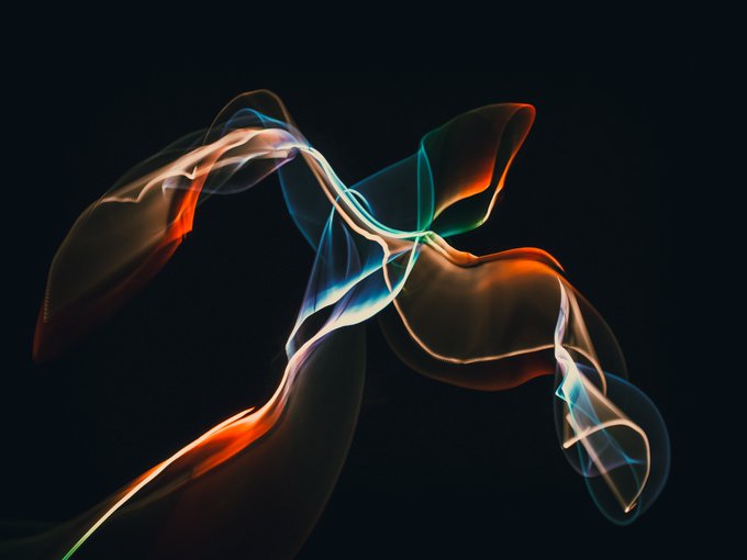 An abstract digital artwork showing flowing, translucent ribbons of orange, blue, and white light against a black background.
