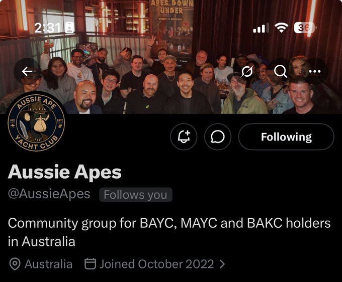 The image shows a group of people posing for a photo with their phones held up at various angles. The main focus of the image is a person holding a phone that has "AUSCIE APES" written on it, indicating they are part of an Australian social media group called "Auscie Apes". The post also mentions that the group is in Australia and invites followers to join them for a special event.