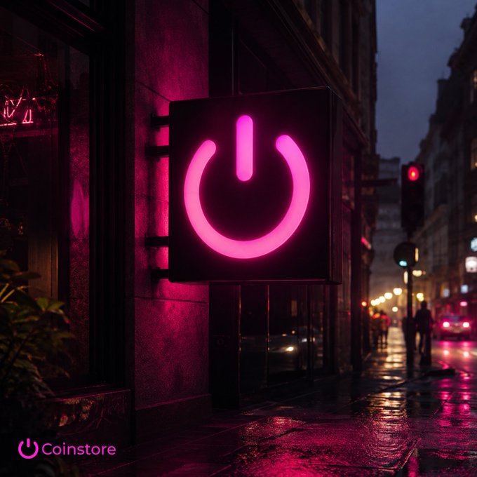 A neon pink power-button style sign hangs on a building at night on a wet city street, with the 'Coinstore' logo in the lower-left corner.