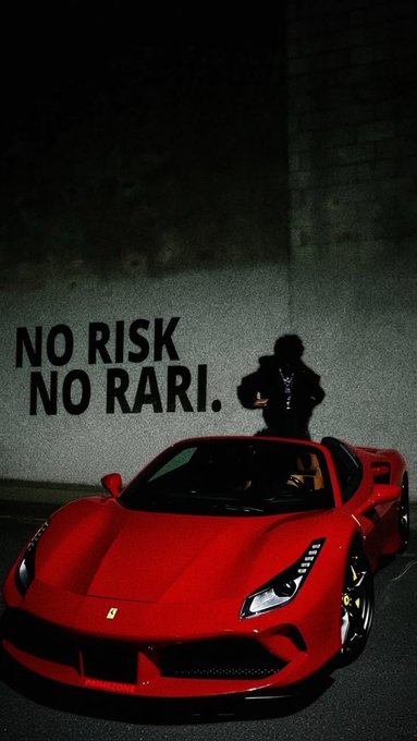 A red Ferrari sports car is parked against a concrete wall featuring the graffiti-style text "NO RISK NO RARI," with a person standing behind the vehicle, embodying the post's message that taking risks leads to wealth.