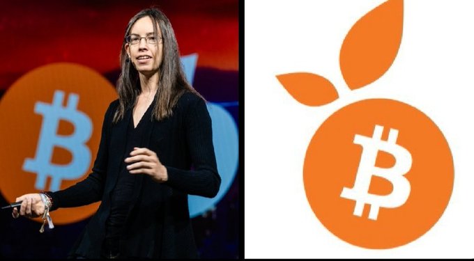 Bitcoin advocate Lyn Alden stands on stage in front of an orange Bitcoin logo, while the right side displays the same orange-themed Bitcoin emblem tying into the launch of her "Orange Juice" permanent capital company, which has raised $40M to build a Bitcoin treasury-focused investment vehicle.