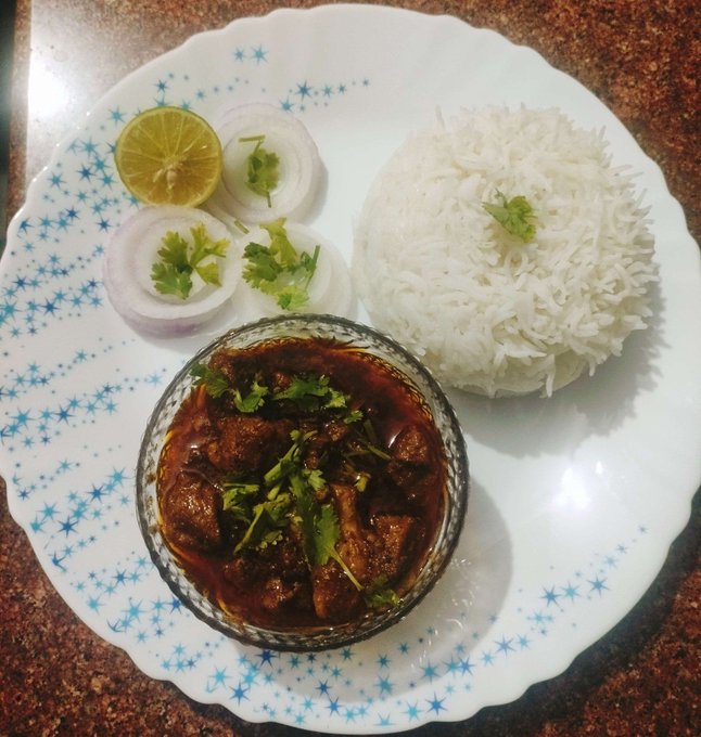 A plate of chicken curry with basmati rice, garnished with cilantro, lemon, and onion rings. The home-cooked meal aligns with the post's mention of cooking chicken and rice as part of a weekend of self-care.