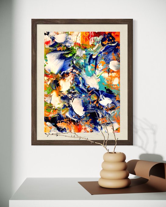 A framed abstract painting with blue, green, red, and white brushstrokes hanging above a white console table with a beige sculptural vase holding bare branches.