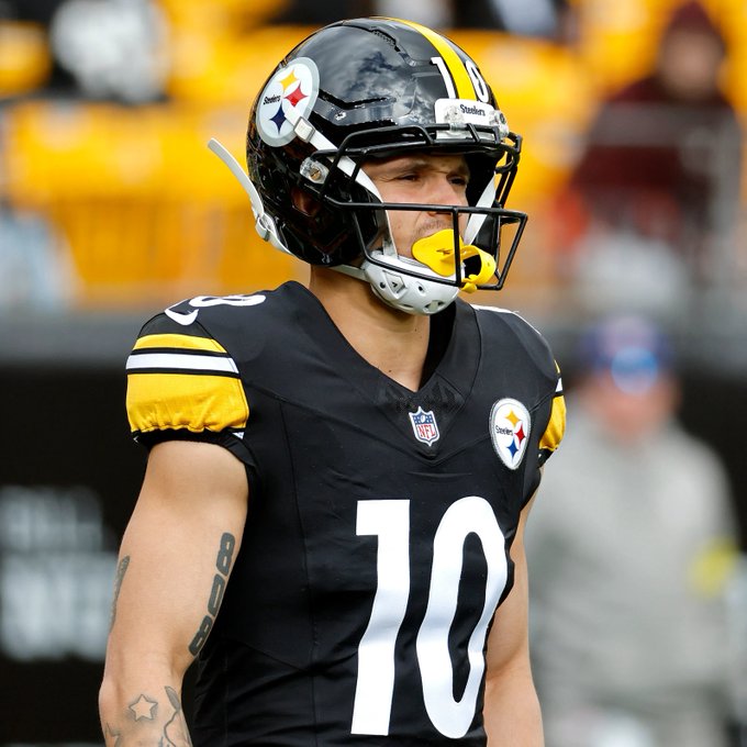 An American football player wearing a Pittsburgh Steelers black jersey with number 10 and helmet stands on the field with a yellow mouthguard. A 'Heinz' logo appears on the helmet.
