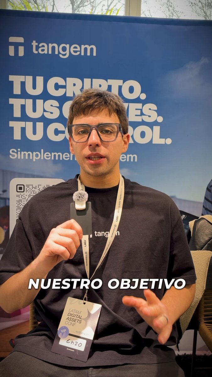 A man with glasses wearing a Tangem-branded shirt and lanyard stands in front of a 'Tangem' banner reading 'TU CRIPTO. TUS... TU CONTROL.' with overlay text 'NUESTRO OBJETIVO'.