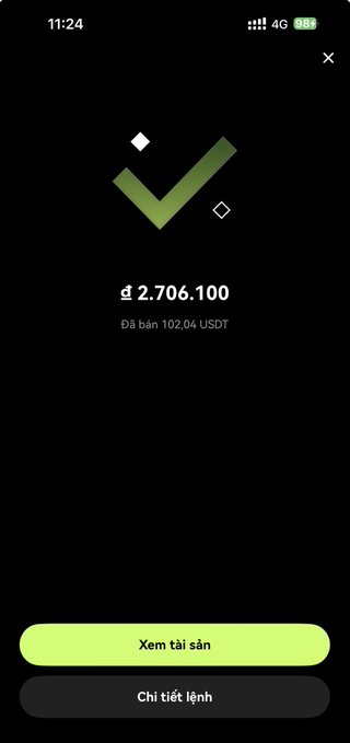 A mobile app confirmation screen displaying a green checkmark and a balance of ₫ 2.706.100 (≈102.04 USDT), with buttons 'Xem tài sản' and 'Chỉ tiết lệnh'.