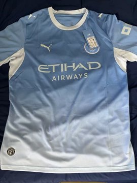 A light blue Manchester City home jersey with Puma logo, Etihad Airways sponsor, and the Premier League badge.