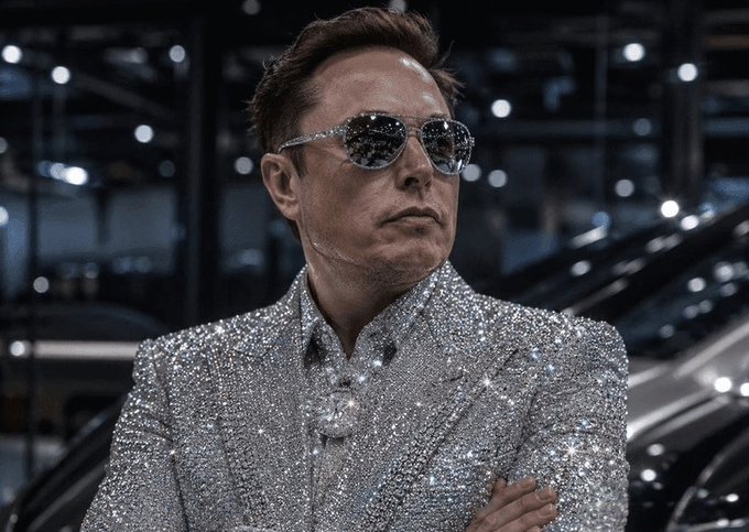 The image features a man wearing a silver suit with diamond-like embellishments, sunglasses, and standing next to a car. The caption suggests that he might be involved in the automotive industry or has some connection to it.