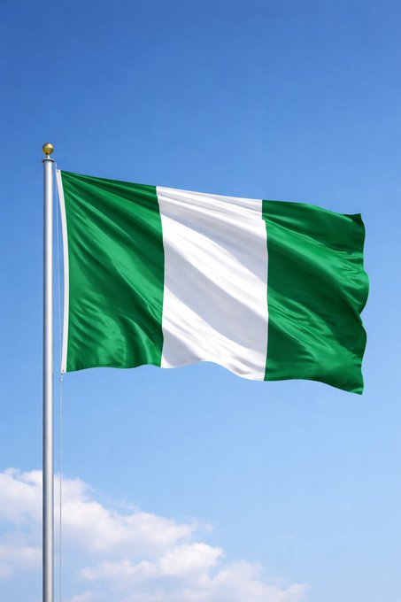 The flag of Nigeria, with its green-white-green vertical stripes, waves against a clear blue sky on a flagpole.