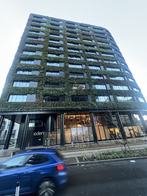 The "eden" hotel features a striking multi-story building covered in lush green vegetation, creating a living facade that contrasts with its modern black architectural frame. The name "gGRID" in the post likely refers to the grid-like pattern formed by the building's structured window and plant arrangement.