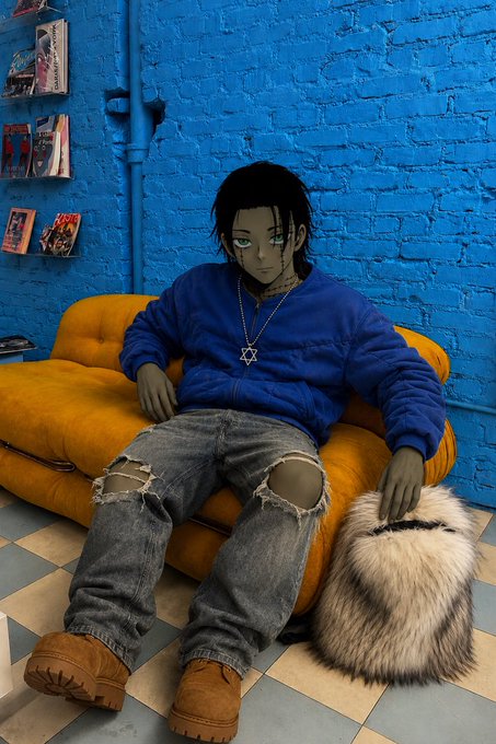 An anime-style illustration shows a person with dark hair and a Star of David necklace wearing a blue sweater and ripped jeans, sitting on a yellow couch next to a furry bag against a bright blue brick wall.