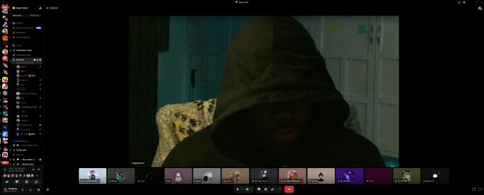 A Discord video call screenshot showing a person wearing a dark hoodie in low lighting, with multiple participant thumbnails visible along the bottom of the screen, related to the "superdadsdao" community hangout.