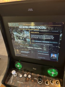 A close-up of a custom Raspberry Pi arcade cabinet displays the "Ocean Protocol" mission briefing screen for the game "Bitcoin Blitz," with a "PROCESS STARTING" prompt visible, tying into the developer's post about completing the 20-level community game ahead of its September 19th Noderunners conference launch and ongoing efforts to make it playable on a Pi4.