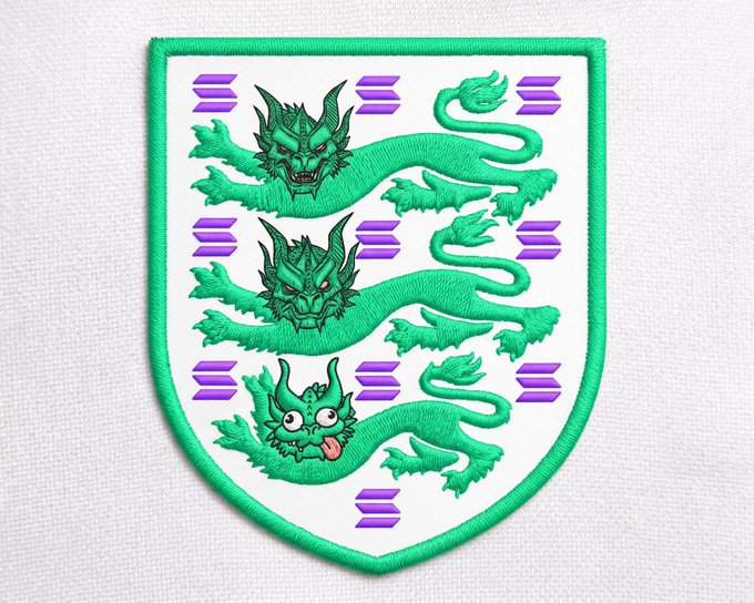 An embroidered shield-shaped patch with a green border displays three green dragons with purple and pink striped backgrounds, with the bottom dragon having a cute cartoonish face.
