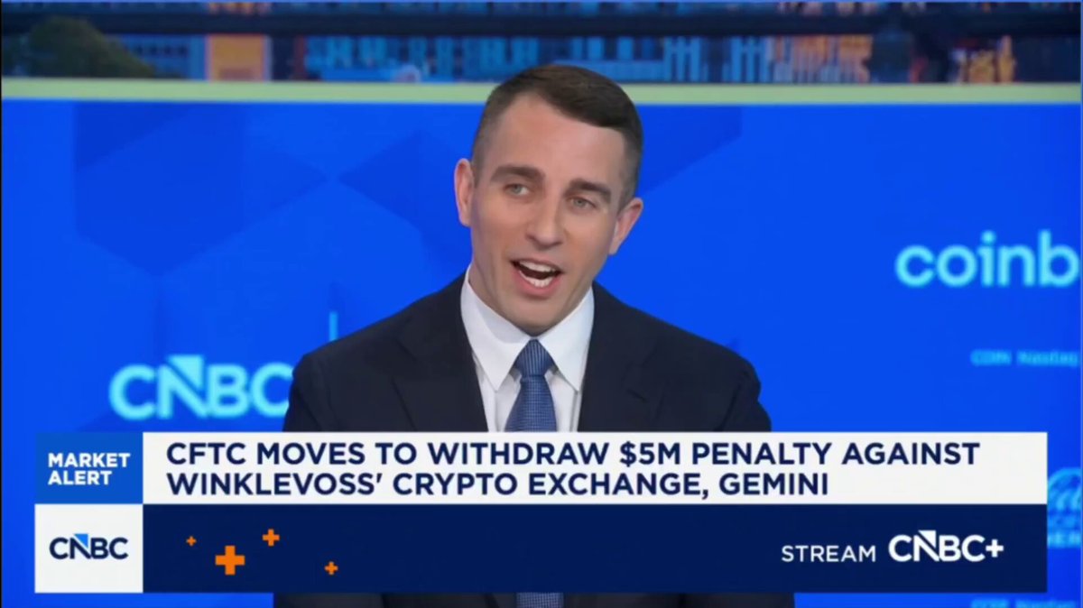 The image features a man wearing a suit, standing behind a computer screen with a news anchor talking about cryptocurrency. The man appears to be discussing the potential of Bitcoin as an investment opportunity or the impact of government policies on the cryptocurrency market.